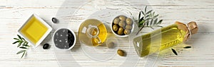Flat lay with bottle, jug, bowl with olive oil and olives on background, space for text