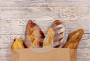 Flat lay. Bread in a paper bag on a wooden table.