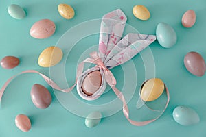 Flat lay with bunny ears napkin and Easter eggs on blue background. Easter celebration concept. Top view