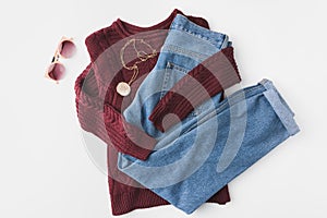 flat lay with burgundy knitted sweater, trendy jeans and accessories,