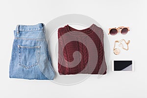 flat lay with burgundy knitted sweater, trendy jeans, accessories and smartphone,