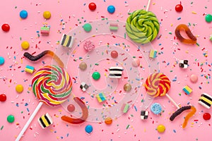 Flat lay of candies festive background with assortment of colourful caramel with jelly and sprinkles over pink