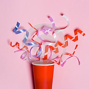 Flat lay of Celebration. Paper cup with colorful party streamers