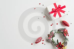 Flat lay of Christmas composition, gift box, wreath plant on white background copy space minimal style. Christmas ornament