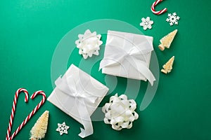 Flat lay Christmas composition with white gift boxes and decorations on green background. Top view