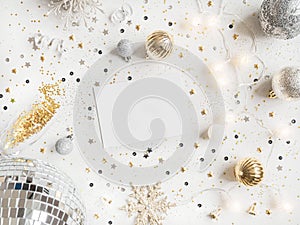 Flat lay of Christmas party disco ball, garland, season decoration and empty white postcard on white background