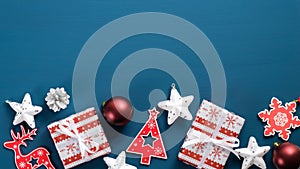 Flat lay Christmas red and white decorations on blue background with copy space. Top view wooden ornaments, gift boxes wrapped