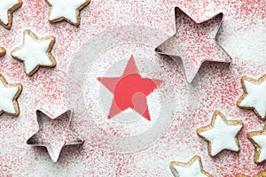 Flat lay of christmas star cookies with cutters and sugar powder in form of snow on red background minimal creative concept