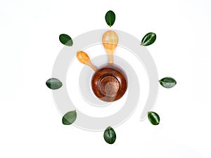 Flat lay of clock tells time with wooden bowl spoon and green leaves.