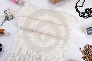 flat lay closeup on handmade white woolen scarf with diferent accessories