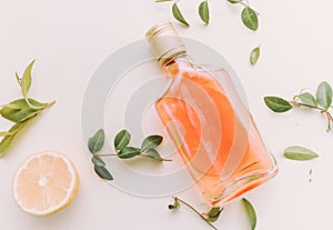 Flat lay of cold refreshing summer alcohol cocktail with fresh lemon , orange mint and ice bottle over white marble background, fl