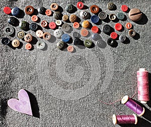 Flat lay of colorful buttons and sewing threadon linen background