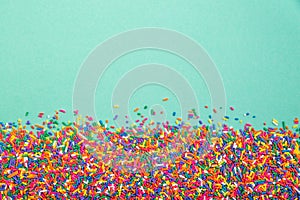 Colorful sprinkles on bottom of green background photo