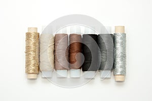 Flat lay colorful cotton thread spools, embroidery yarn, white, brown, gray, black, silver, gold bobbins, mock up, top view.