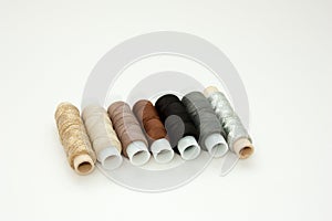 Flat lay colorful cotton thread spools, embroidery yarn, white, brown, gray, black, silver, gold bobbins, mock up, top view.