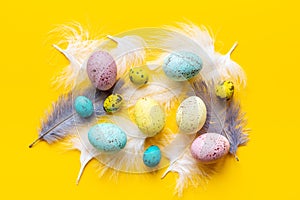 Flat lay of colorful Easter eggs and birds feather, top view