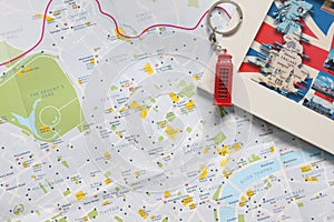 A flat lay of a colorful London map with a red souvenir telephone booth and a post card