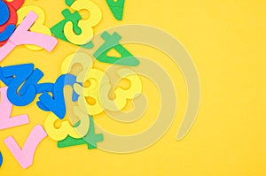 Flat lay of colorful wooden numbers on a yellow surface - space for text
