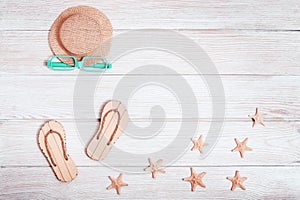 Flat lay of composed miniature of beach lounge area with summer shoes, hat, starfish, sunglasses