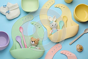 Flat lay composition with baby accessories and bibs on light blue background