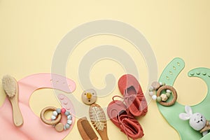 Flat lay composition with baby accessories and bibs on yellow background, space for text