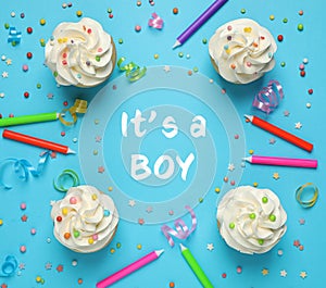 Flat lay composition with baby shower cupcakes for boy on blue background