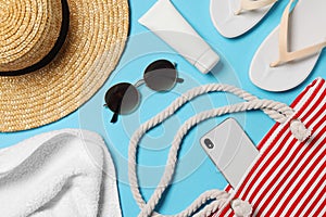 Flat lay composition with bag and other beach accessories on light blue background