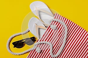 Flat lay composition with bag and other beach accessories on yellow background