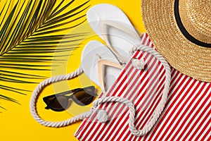 Flat lay composition with bag, palm leaf and other beach accessories on yellow background