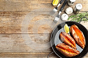 Flat lay composition with baked sweet potatoes in dish on wooden background