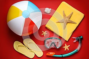 Flat lay composition with ball and beach objects on red background