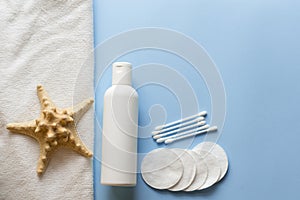 Flat lay composition with Bath skincare products.milk, cotton pads, sea star . blue spa background. top view