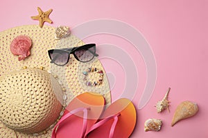 Flat lay composition with beach accessories on pink background. Space for text