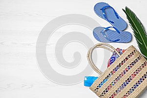 Flat lay composition with beach bag and accessories on white wooden background