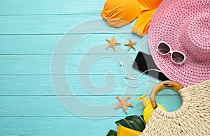 Flat lay composition with beach on light blue wooden background, space for text