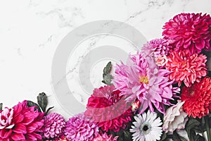 Flat lay composition with beautiful dahlia flowers on white marble background. Space for text