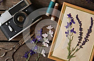 Flat lay composition with beautiful dried flowers, vintage camera and photo frame on wooden table