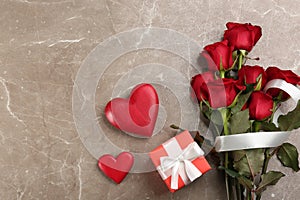 Flat lay composition with beautiful red roses and gift box on grey background, space for text. Valentine`s Day celebration