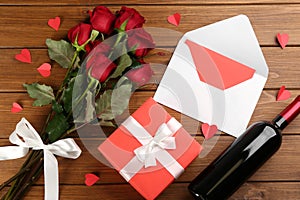 Flat lay composition with beautiful red roses and gift box on wooden background. Valentine`s Day celebration