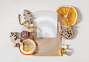 Flat lay composition with blank greeting card and Christmas decor on white wooden table, space for text