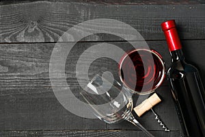Flat lay composition with bottle of wine, glasses and corkscrew on wooden background