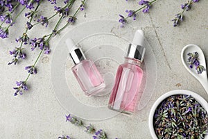 Flat lay composition with bottles of natural lavender essential oil on stone background