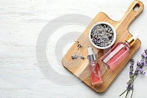 Flat lay composition with bottles of natural lavender essential oil on white wooden background