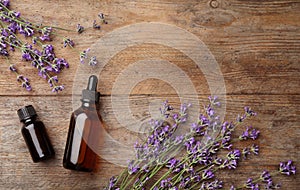 Flat lay composition with bottles of natural lavender essential oil on wooden background