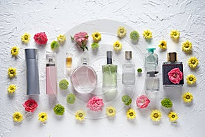 Flat lay composition with bottles of perfume and flowers on white textured background