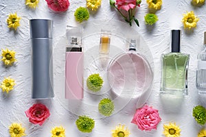 Flat lay composition with bottles of perfume and flowers on white textured background