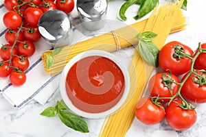 Flat lay composition with bowl of sauce, pasta and tomatoes