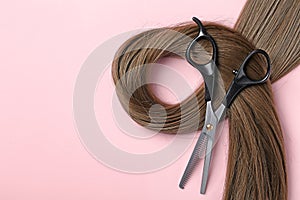 Flat lay composition with brown hair, thinning scissors and space for text on color background.