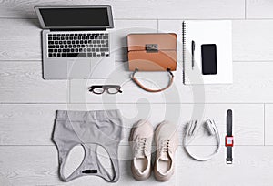 Flat lay composition with business supplies and sport equipment on white wooden floor. Concept of balance between work and life