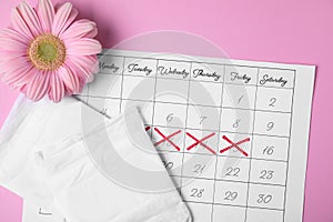 Flat lay composition with calendar, menstrual pads and gerbera flower on color background.